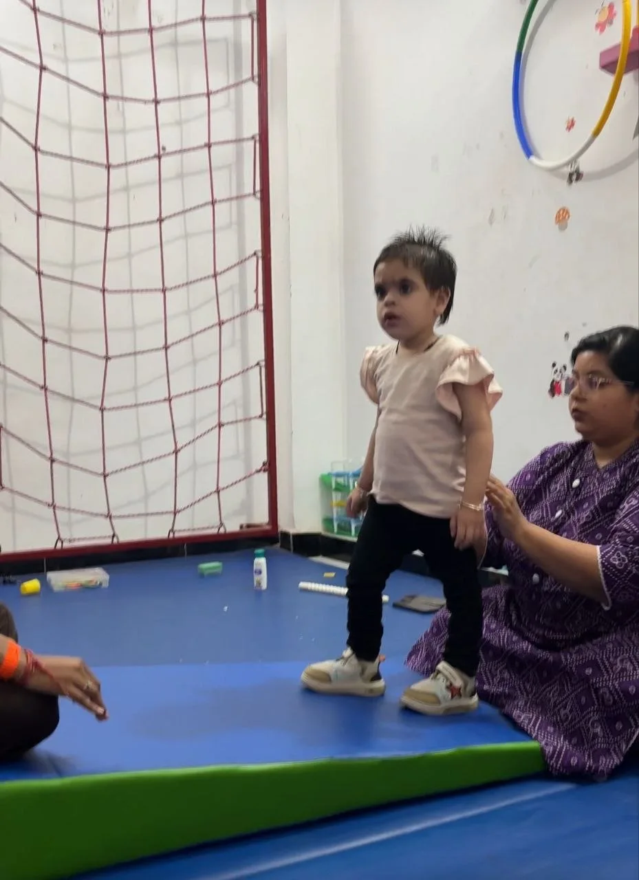 A child practising supported standing with attentive adults
